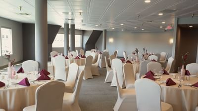 Event space with round tables, white chair covers, and burgundy napkins at London Bridge Resort