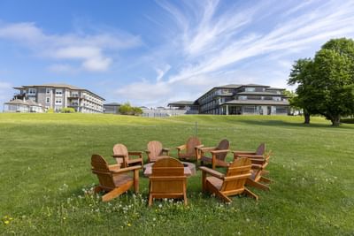 Wooden armchairs arranged in a circle on the grass at Rodd Brudenell River Resort, a premier place to stay in PEI