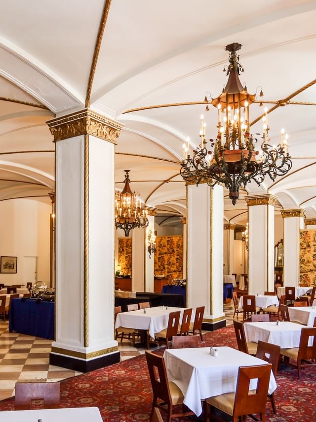 Venetian Dining Room with white tables under ornate chandeliers by gold pillars at Arlington Resort Hotel & Spa