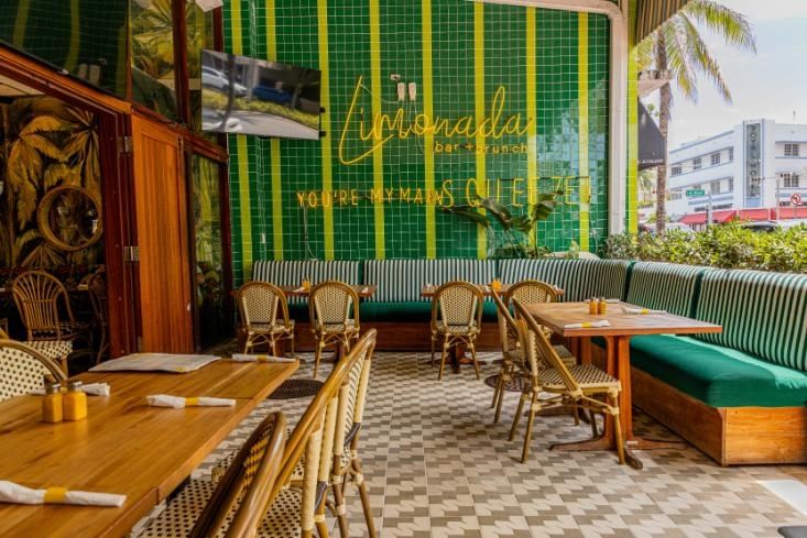 a dining area with green and yellow tiles on the walls and booths and tables and chairs