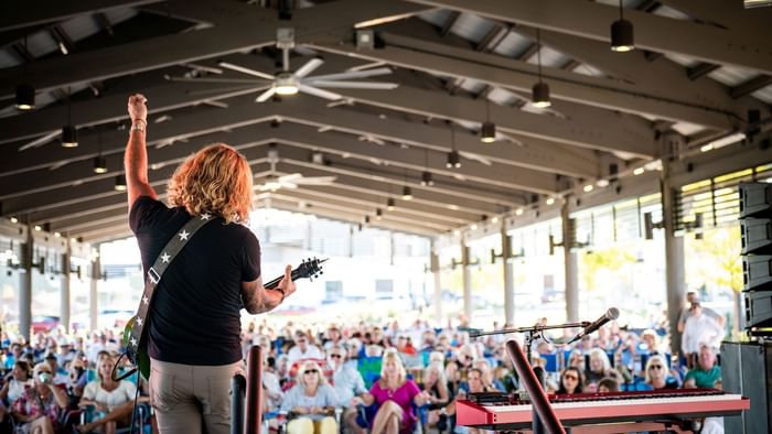 Performer playing guitar and singing for a crowd at Sounds Like Summer event.