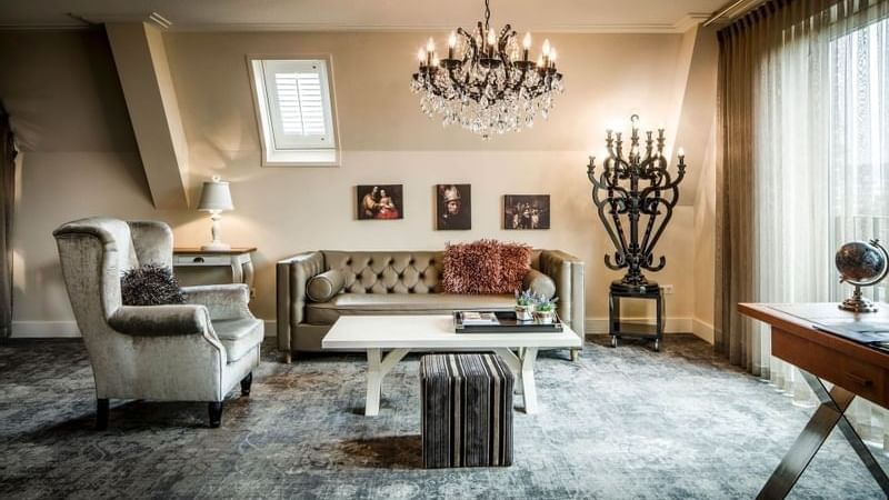 Tufted sofa by a white coffee table surrounding an armchair in luxury suites at Warwick Hotels & Resort