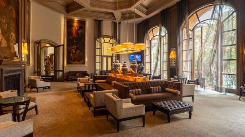 Sophisticated lounge with plush brown sofas, high ceilings, and tall windows at Quinta Real Monterrey