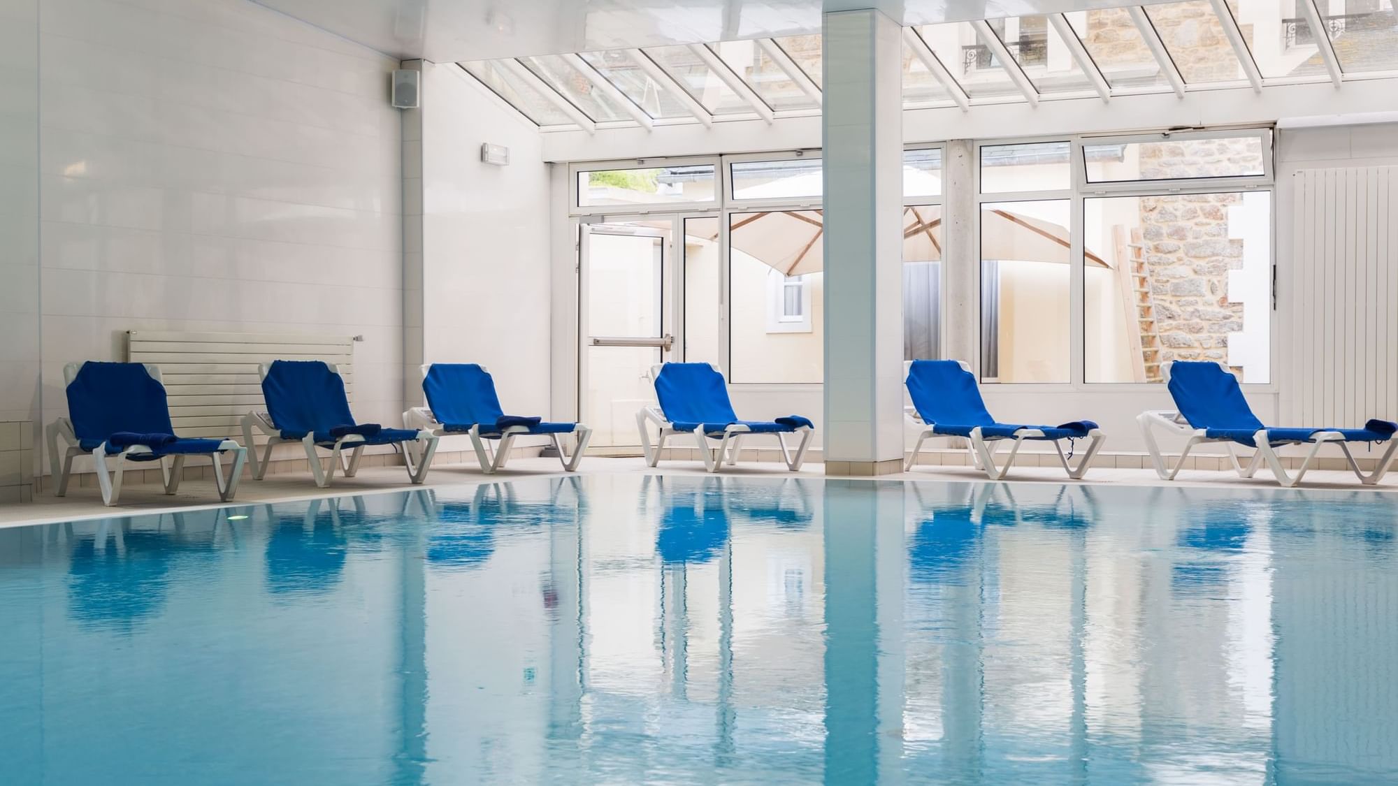 Indoor swimming pool & pool chairs at The Originals Hotels