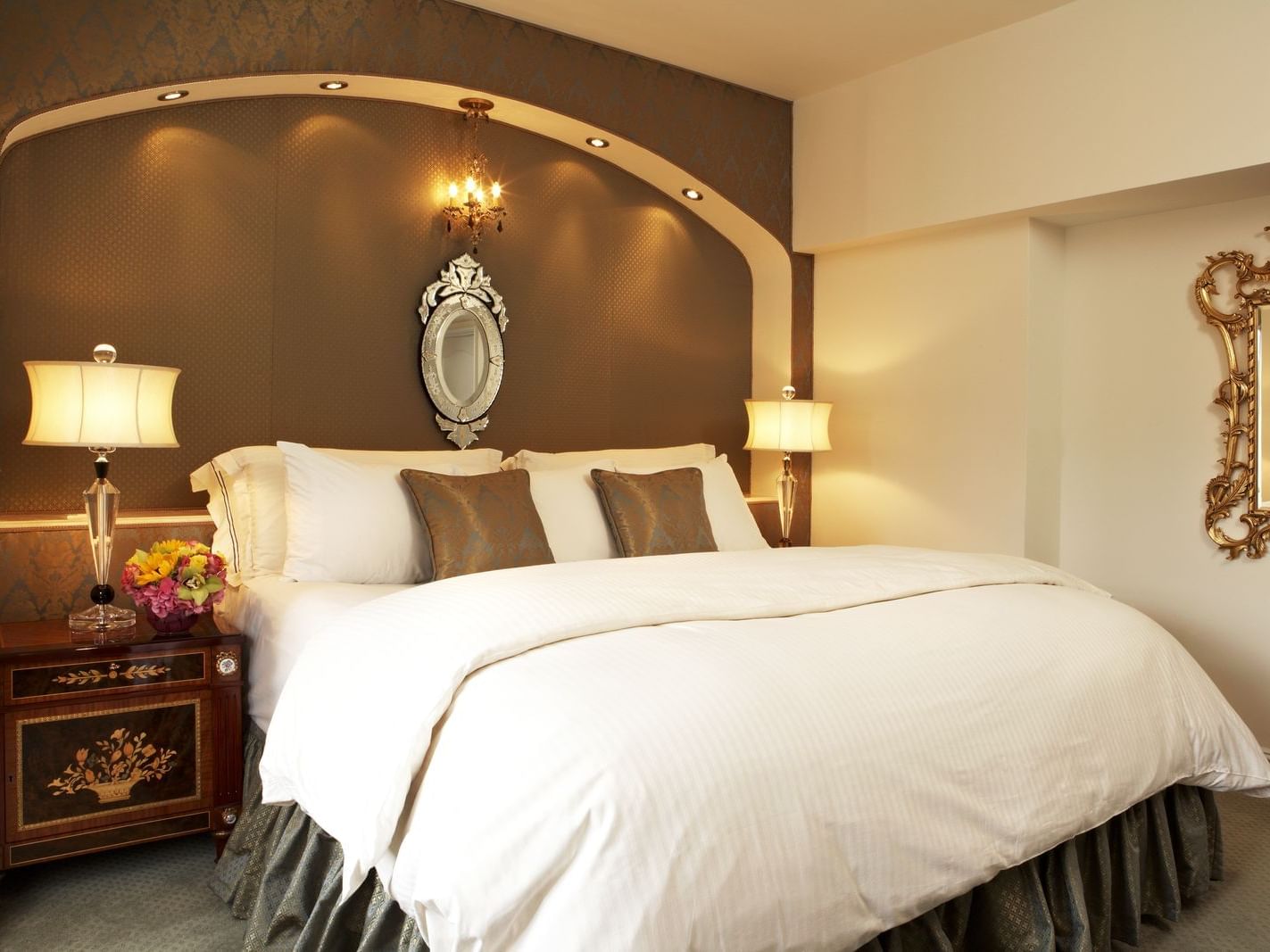 King bed between glowing lamps with a small mirror in Luxury One Bedroom Suite with Two Full Bathrooms at The Kimberly Hotel
