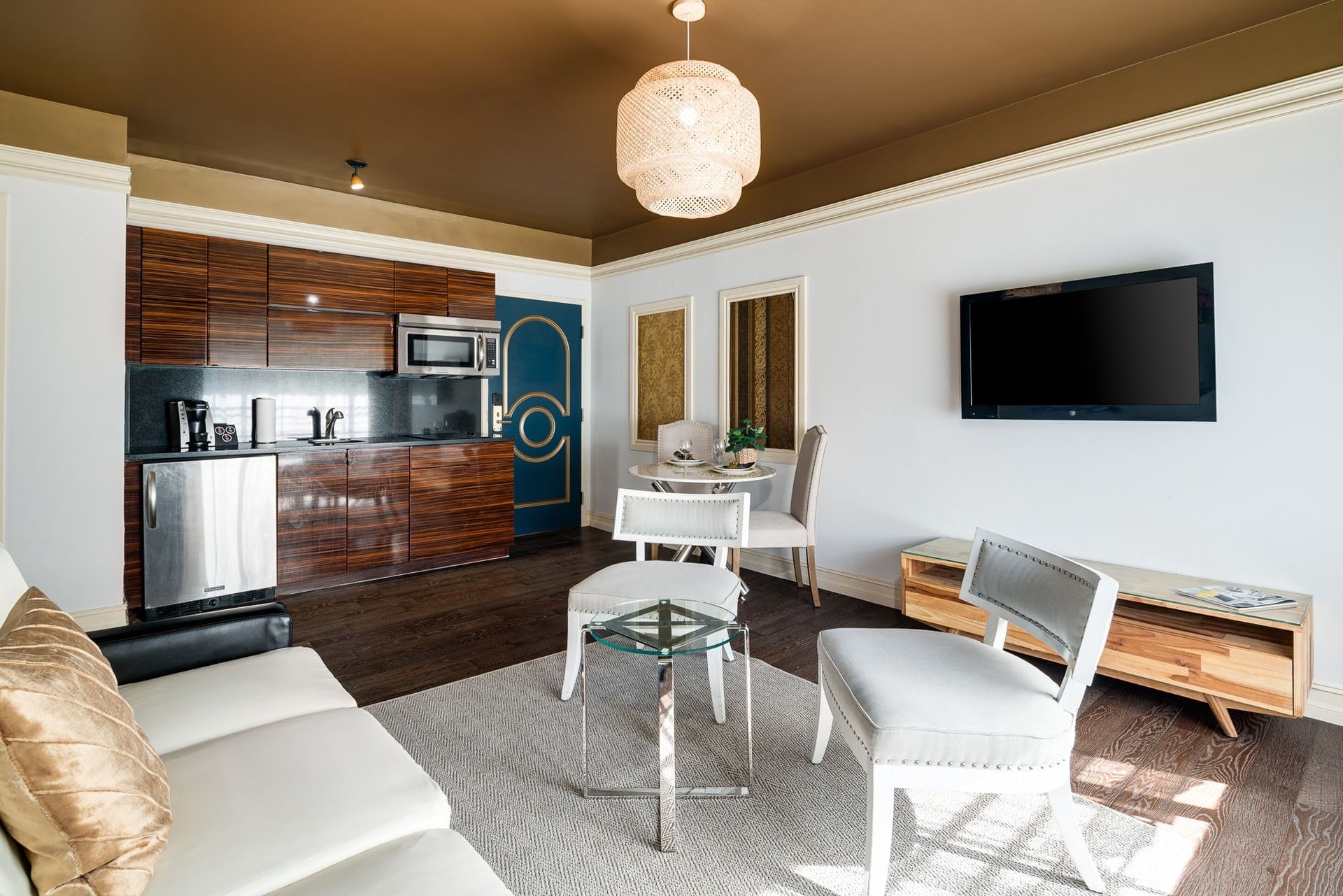 A wide view of a hotel suite with a kitchenette, dining area, living area, and TV