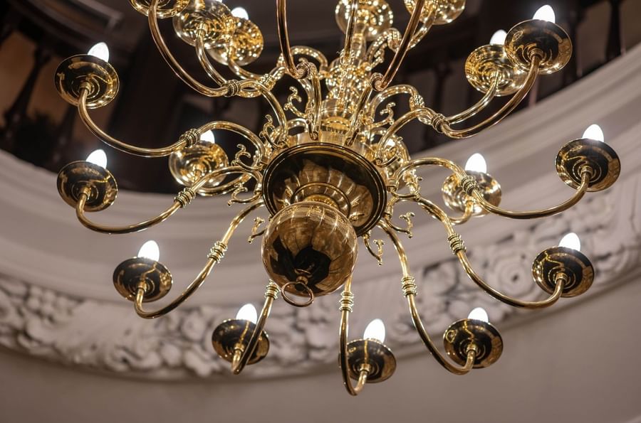 Golden chandelier with glowing bulbs at The Capital Hotel, Apartments and Townhouse