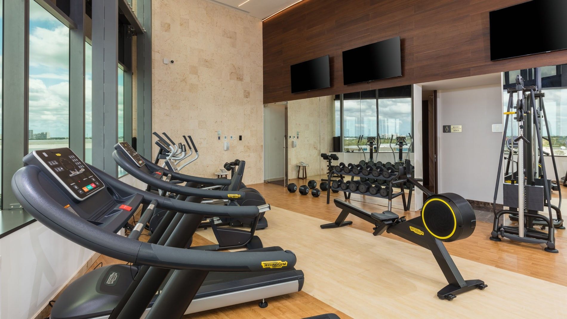 High-end fitness center with treadmills, rowing machines, and weight lifting equipment at Camino Real Merida