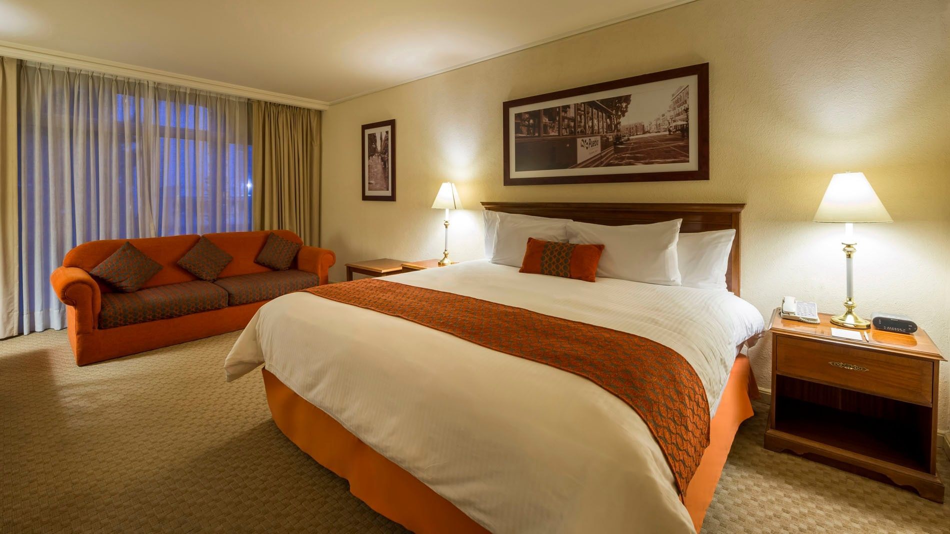 King Camino Real Club featuring a plush king bed and a bright orange sofa at Camino Real Puebla Angelopolis