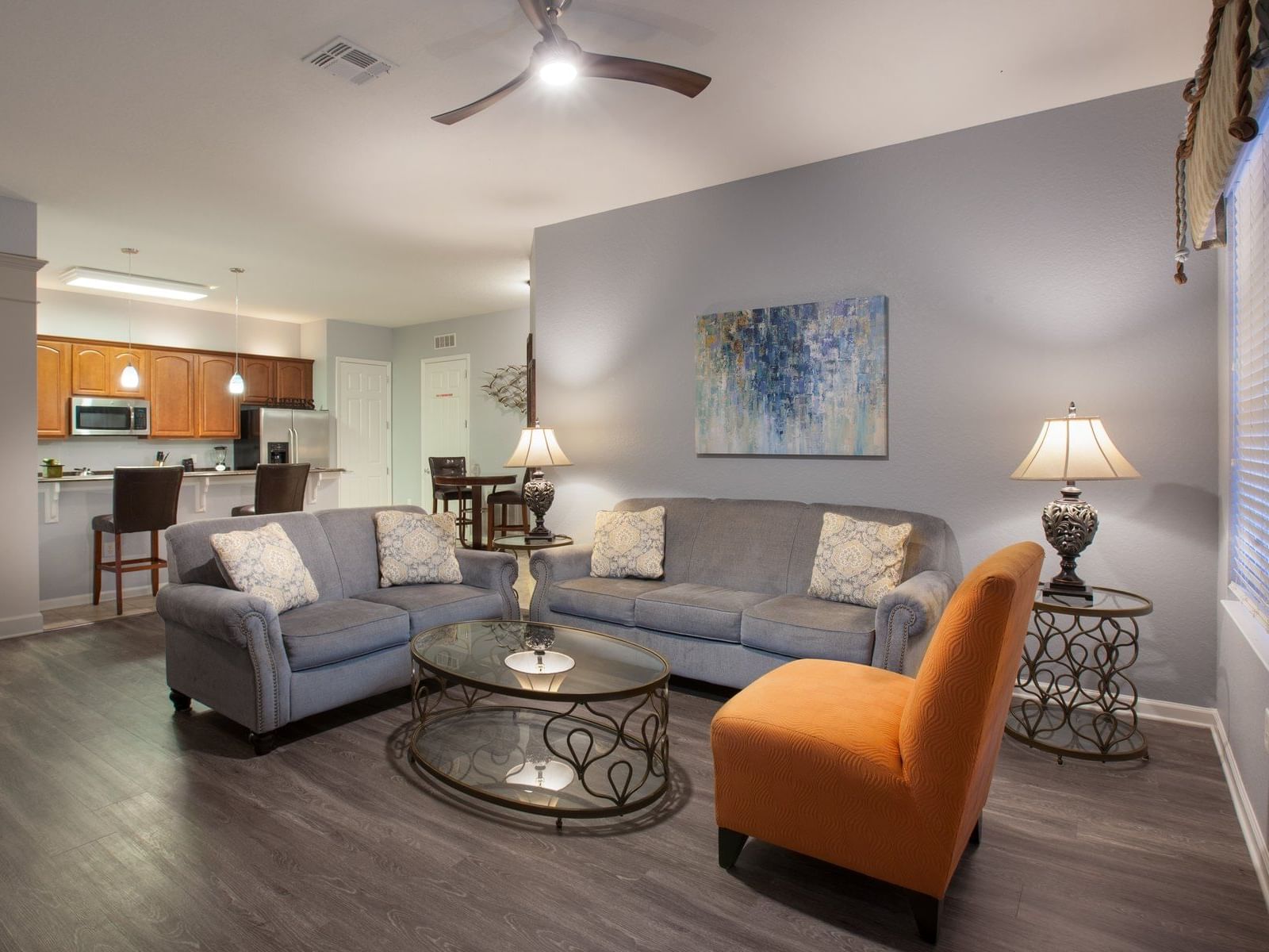Spacious living room with gray sofas, orange accent chair, and open kitchen in Orlando at Vista Cay Resort By Millenium