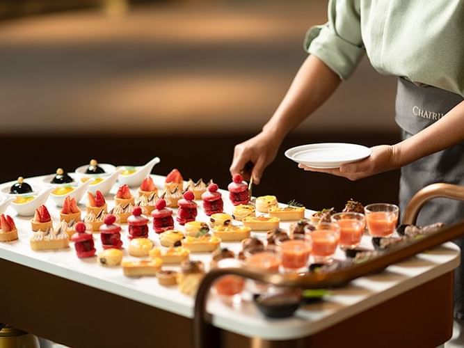 A woman gracefully presents a tray of food, including a delectable dessert
