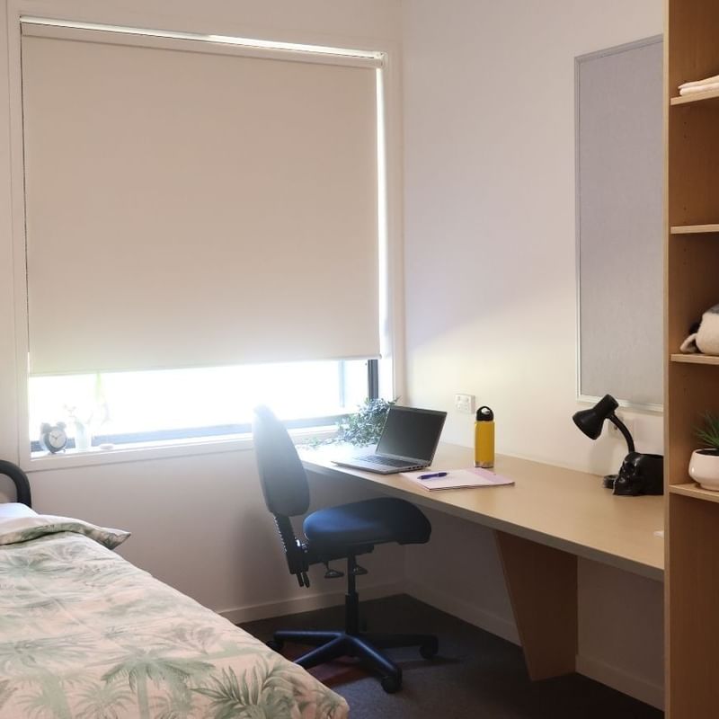Room at La Trobe University Hillside Apartments with bed, desk, and bookshelf.