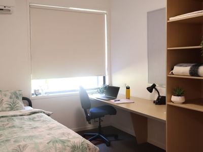 Room at La Trobe University Hillside Apartments with bed, desk, and bookshelf.