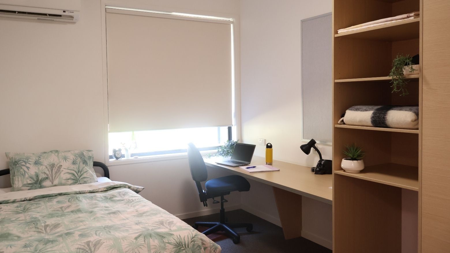 Room at La Trobe University Hillside Apartments with bed, desk, and bookshelf.