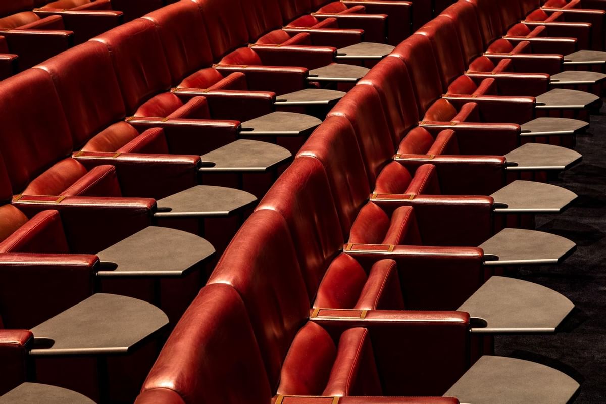 Rows of plush red seats in May Fair Theatre with writing pads at The May Fair Hotel