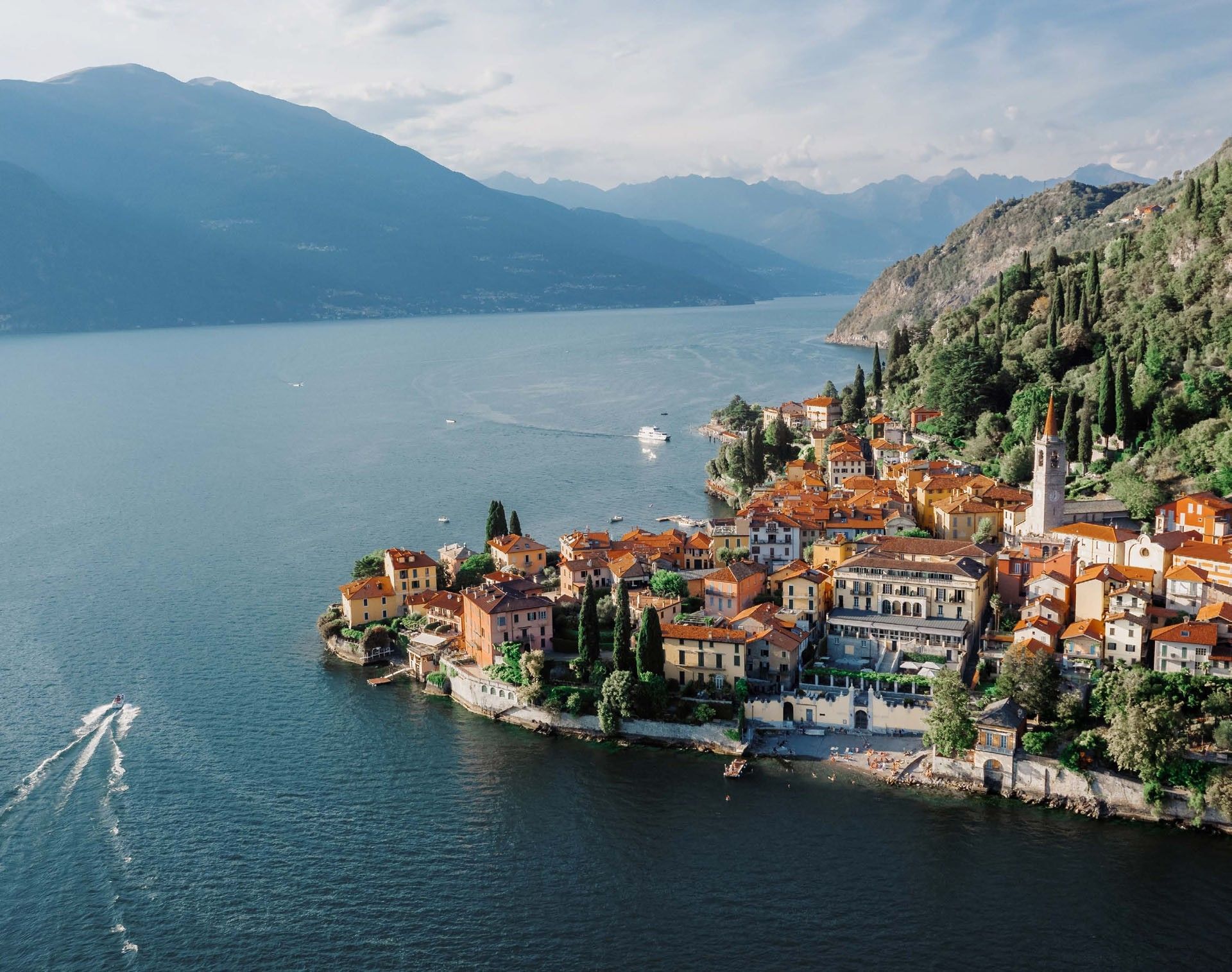 Scenic aerial shot of colorful seaside village Varenna on Lake Como with mountains & blue waters near Meraviglia