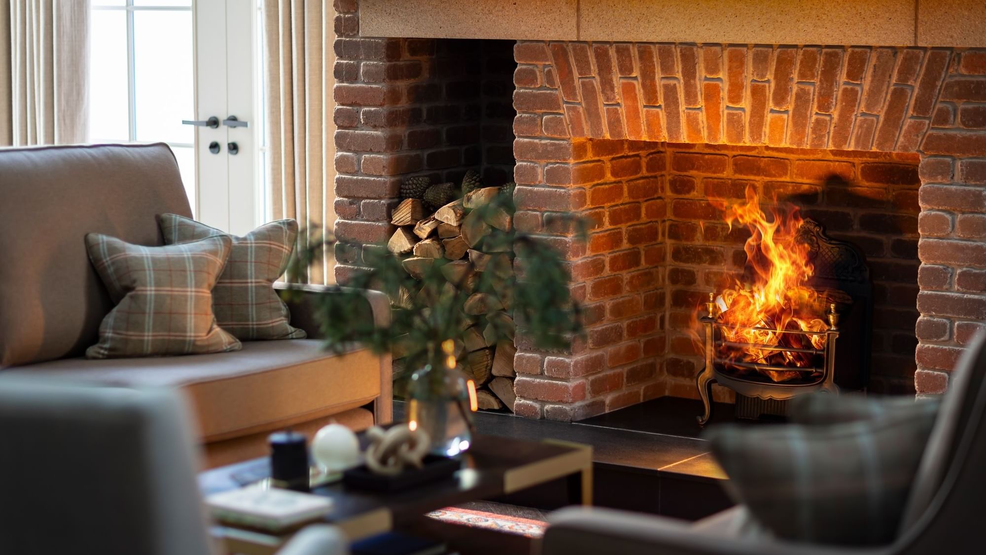 Warm and inviting brick fireplace with a roaring fire and stacked logs, at Dunluce Lodge, providing comfort