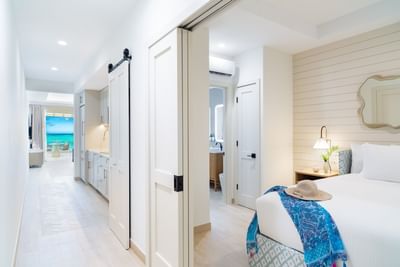 Three Bedroom Beachfront Junior Suite with cozy bed and ocean views through the doorway at Windsong Resort On The Reef