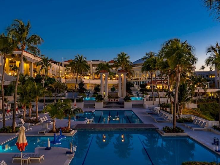 El Conquistador Resort features an illuminated south pool, palm trees, and elegant architecture