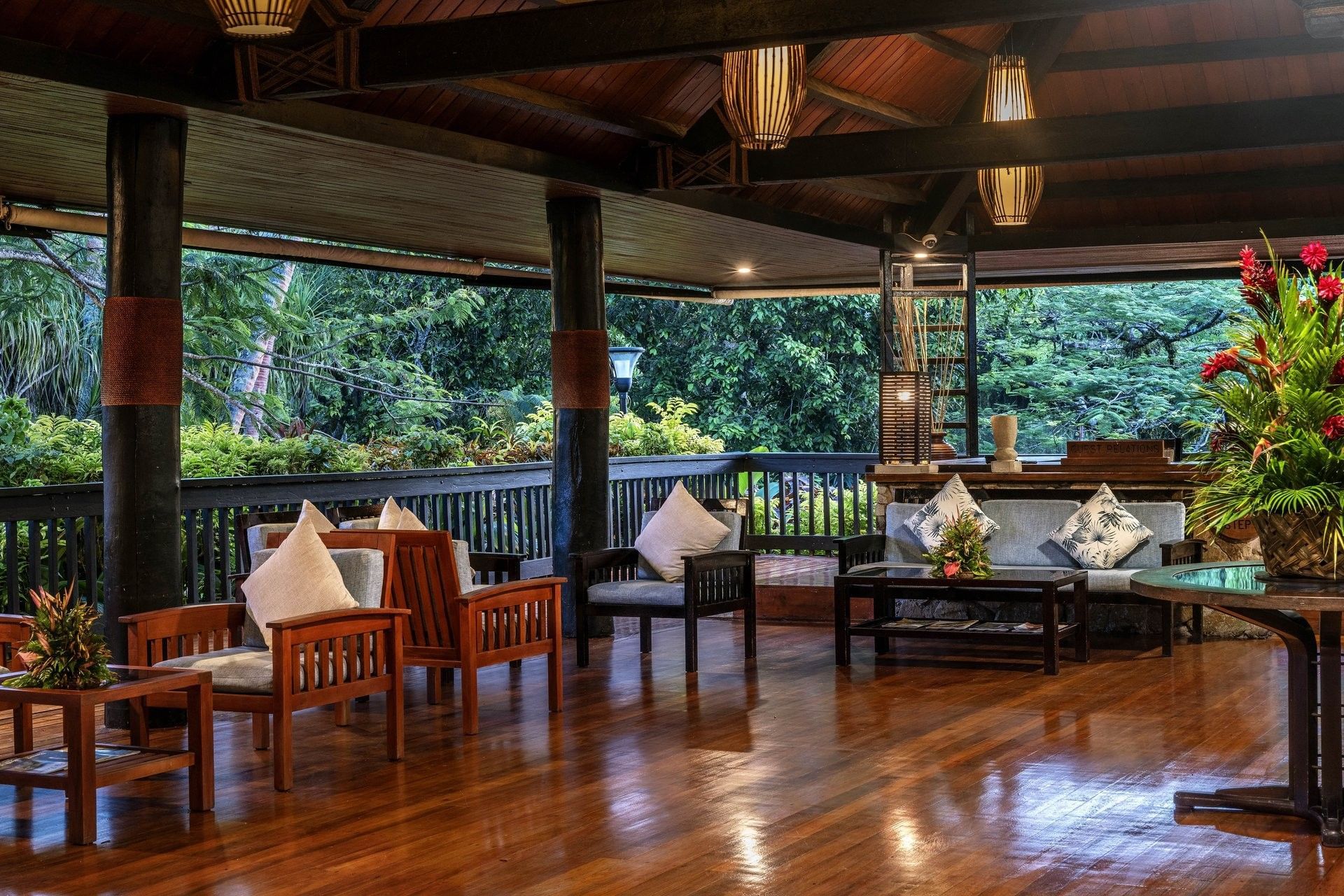 Wooden armchairs and a sofa by a dark railing under a vaulted timber ceiling in the lobby at The Naviti Resort - Fiji