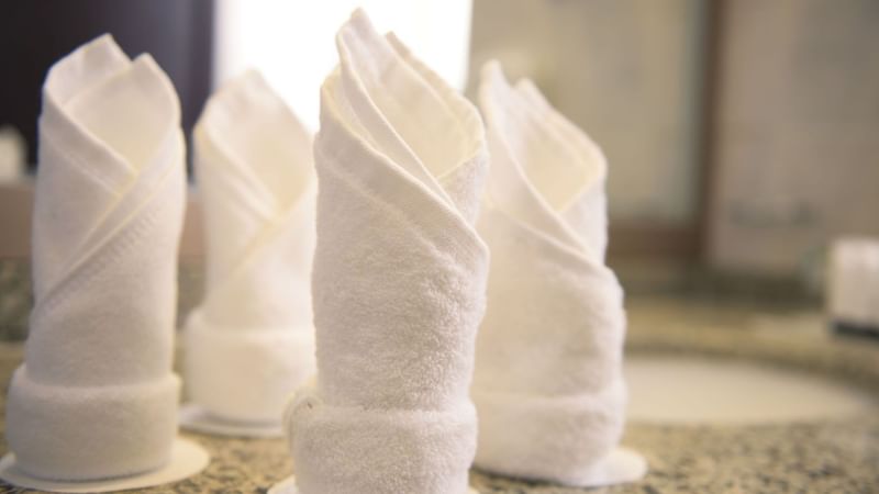 Four folded white towels on a granite countertop in the Executive King Room at Saja by Warwick Madinah.