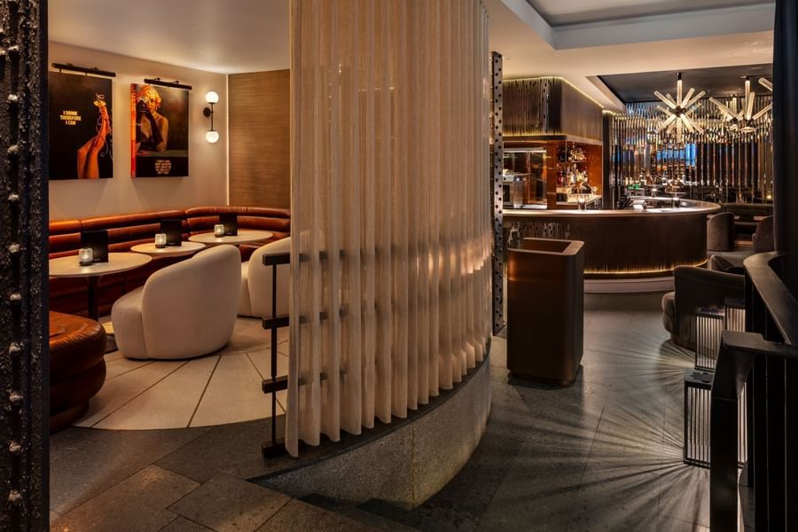 Chic May Fair Bar interior with warm lighting, round tables, plush chairs, and modern art at The May Fair Hotel