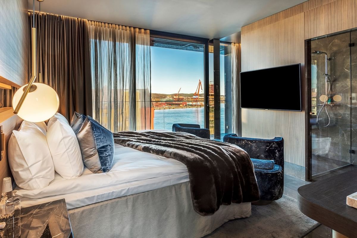 Lyxhotellrum med havsutsikt, stor säng, tv och glasdusch.