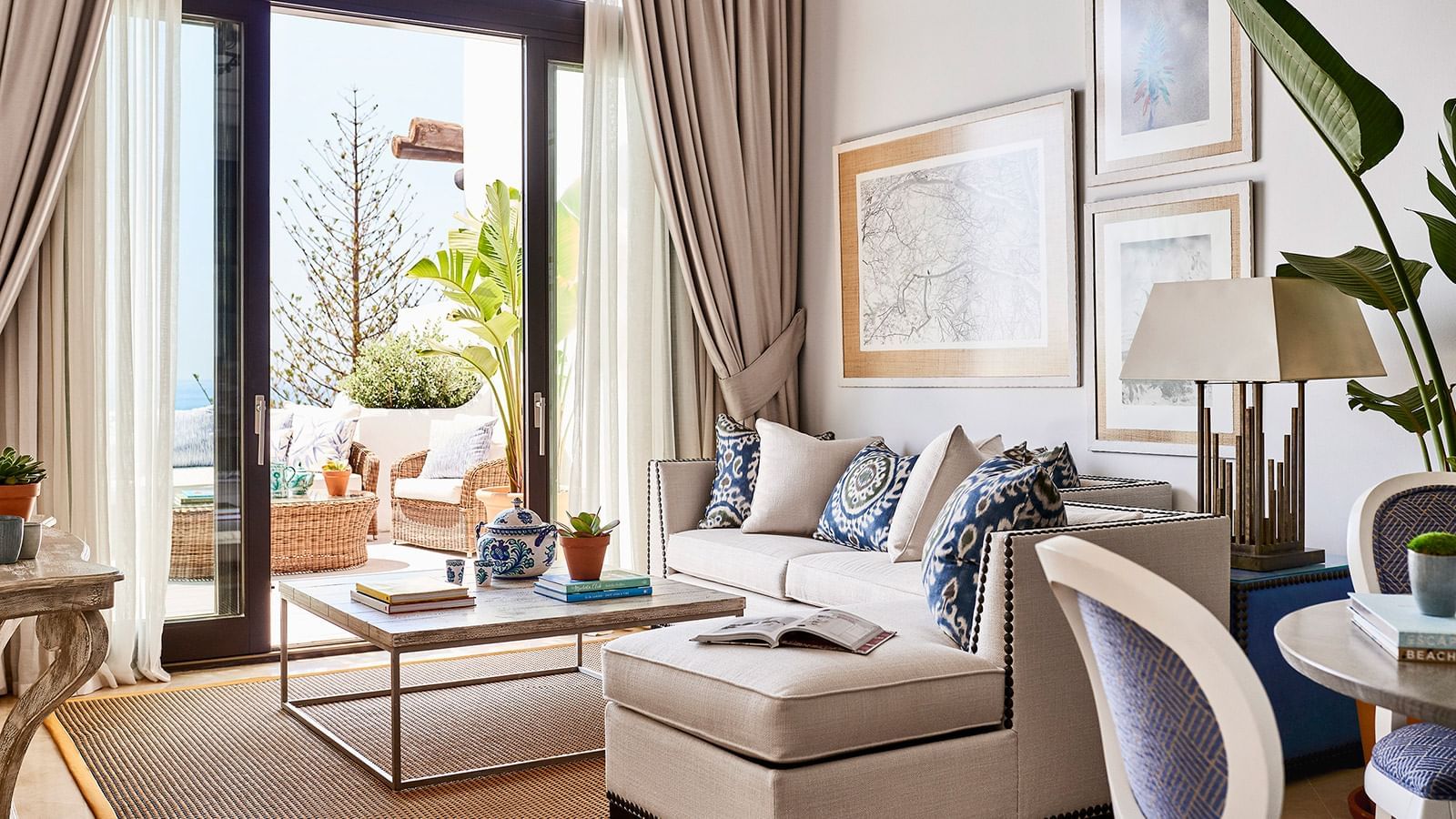 Imperial Beach Suite living room with a sofa, blue patterned pillows, and sliding doors to a terrace at Marbella Club