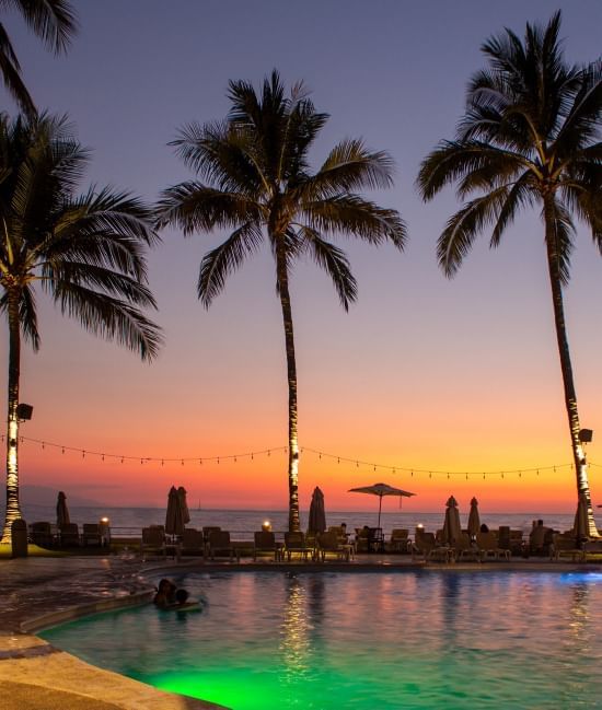 Sunset with palm trees and a pool by the beach at Plaza Pelicanos Club Beach Resort