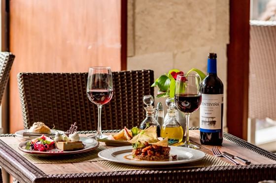 Dining table with Beef kulbasti, dessert, and 2 wine glasses served in Caruso Specialties Restaurant at Plaza Pelicanos Club Beach Resort