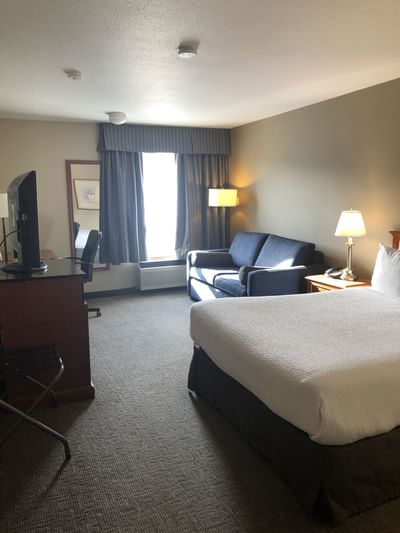 Bed, sofa with TV area in Superior Plus One Queen at Hotels in Fort McMurray