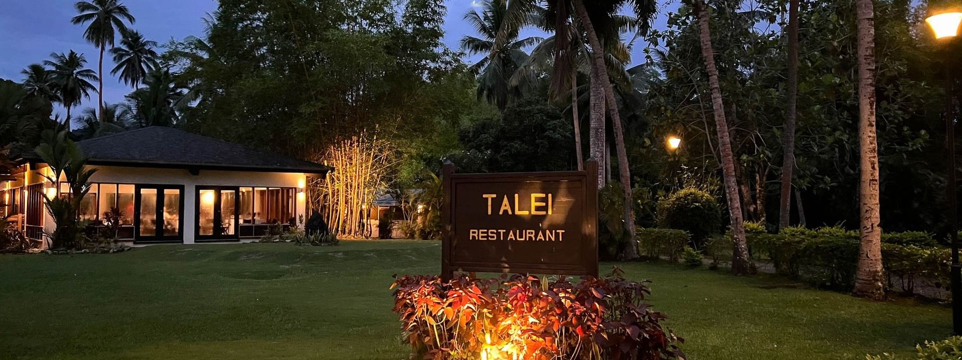Talei Restaurant sign with lit plants and palm trees at The Naviti Resort in Korolevu