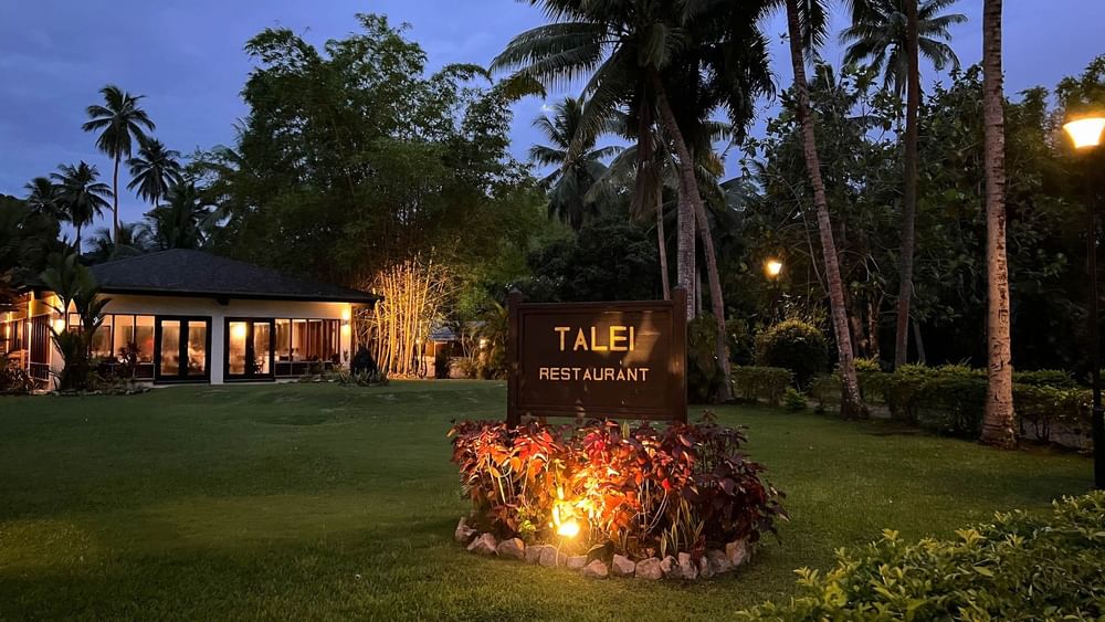 Talei Restaurant sign with lit plants and palm trees at The Naviti Resort in Korolevu.