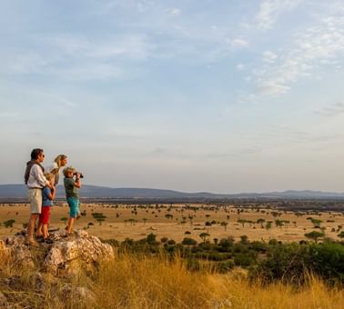 Family standing on a boulder of rocks near Kirawira Serena Camp