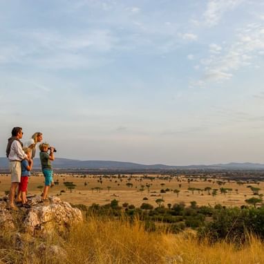 Family standing on a boulder of rocks near Kirawira Serena Camp