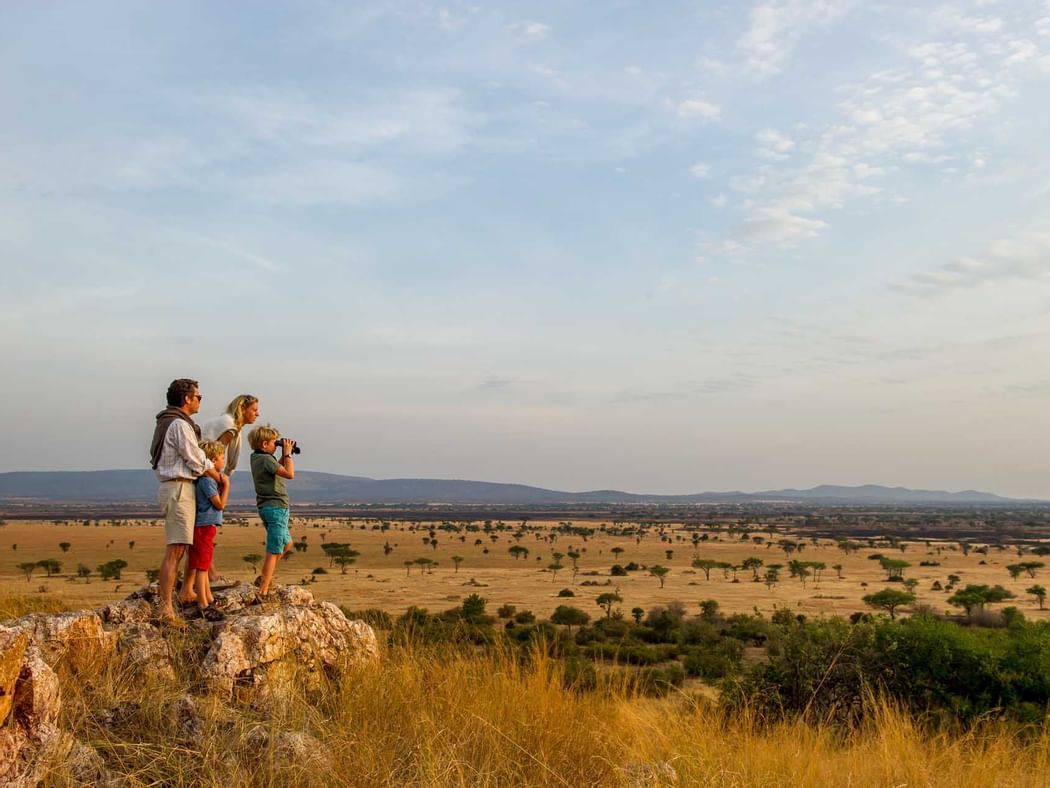 Family standing on a boulder of rocks near Kirawira Serena Camp
