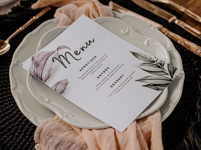 Menu card on a plate on a banquet table set up with placemat & cutlery at Live Aqua Resorts and Residence Club