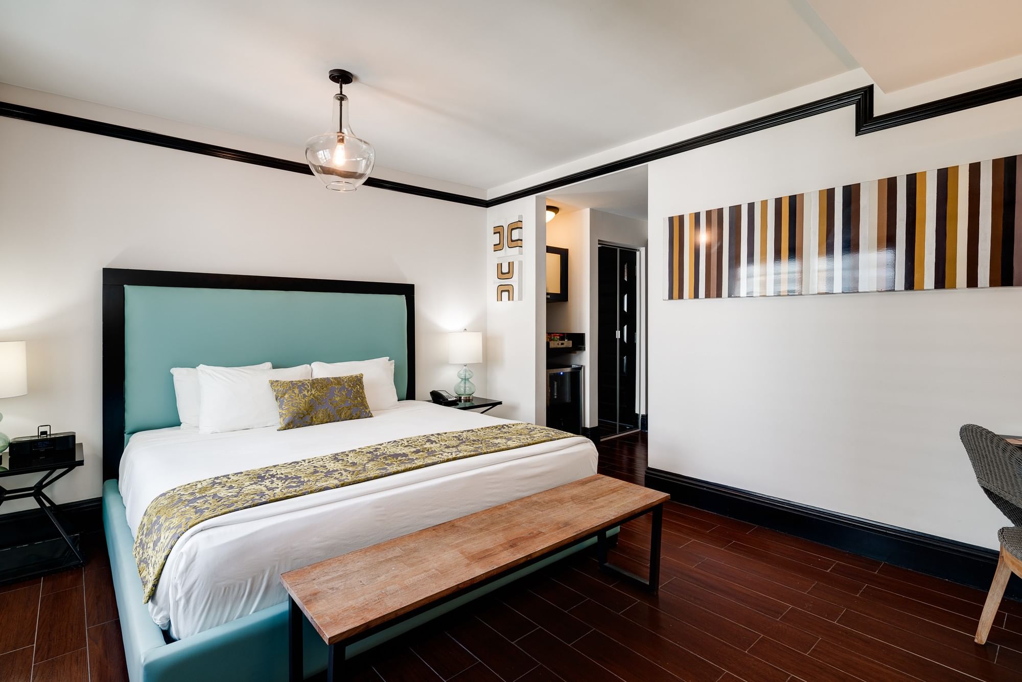 A hotel room with a king-sized bed, wooden bench, and nightstands.