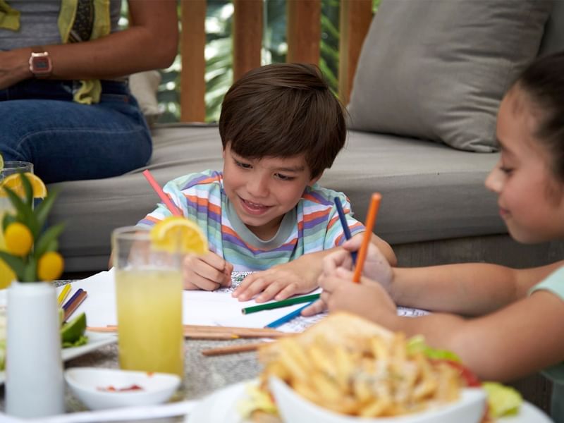 Child coloring at a table with food and drinks in Grand Fiesta Americana