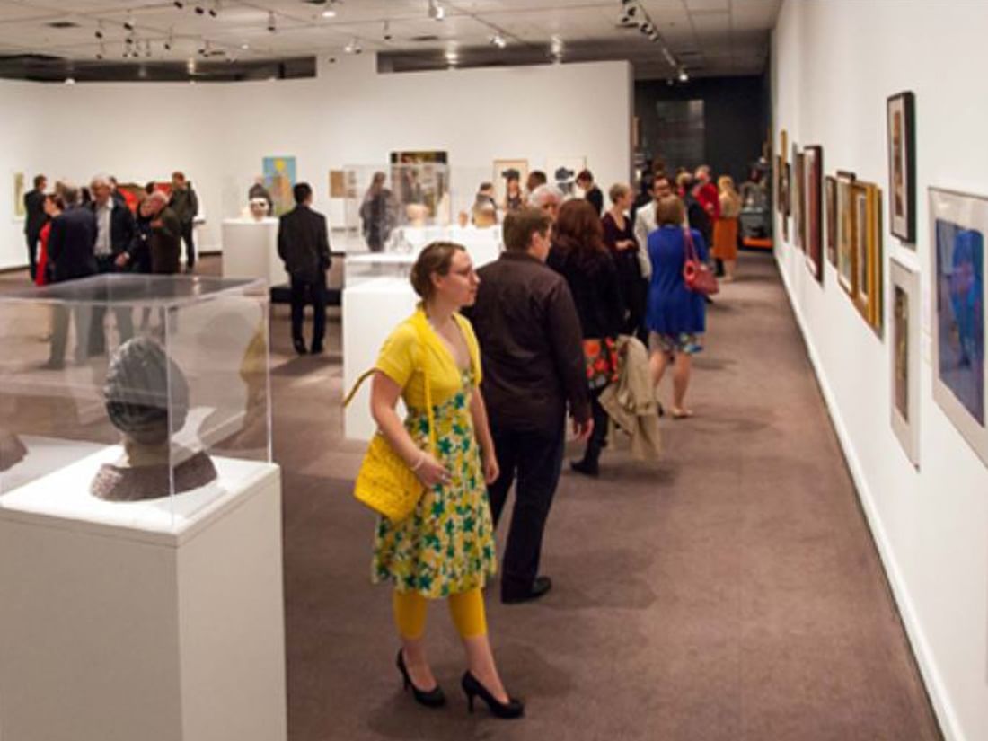 Visitors observing artwork in Glenbow Museum near Acclaim Hotel Calgary