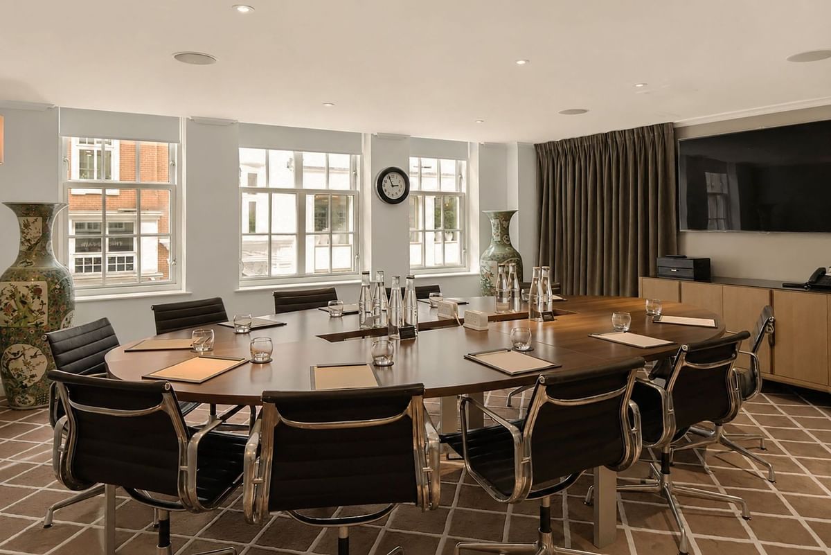Sunlit Private Suite 4 boardroom layout with wooden table, leather chairs  and windows at The May Fair Hotel, London