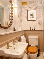 Elegant bathroom with a white sink, wooden toilet, and a shower at The Capital Hotel, Apartments & Townhouse - London.