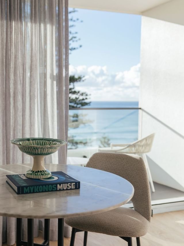 Ocean View King at Elysium Manly with a ceramic bowl atop a book, by sheer curtains, one of the best places to stay in Manly