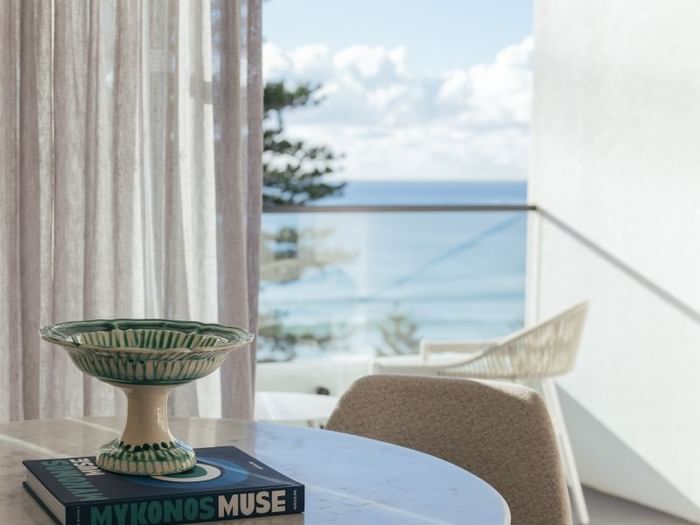 Ocean View King at Elysium Manly with a ceramic bowl atop a book, by sheer curtains, one of the best places to stay in Manly