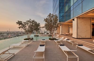 Outdoor swimming pool with sun loungers at Eastin Hotels captured during sunset