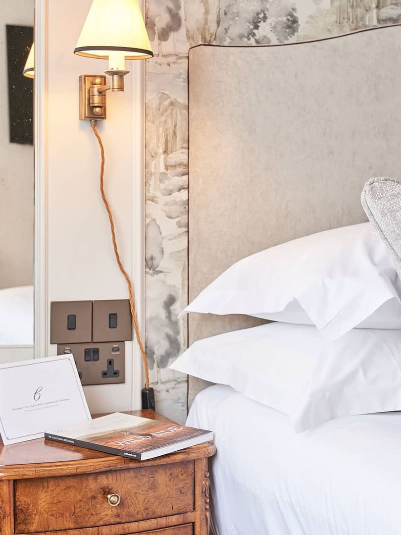 Cozy bedhead with patterned wallpaper next to bedside table with lamp at The Capital Hotel, Apartments and Townhouse