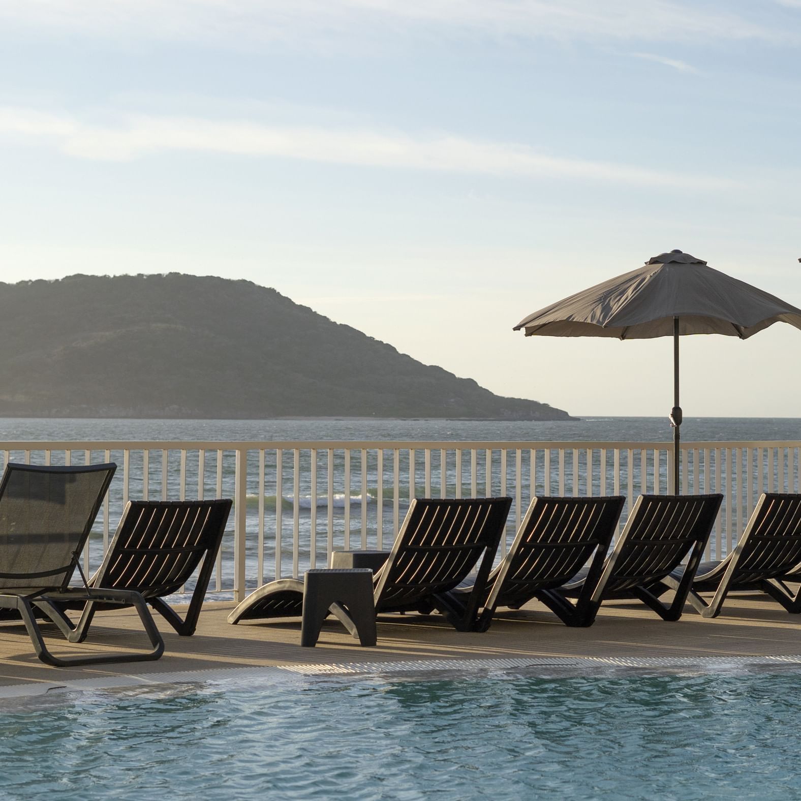 Sun lounges in pool area by the ocean, Viaggio Resort Mazatlan