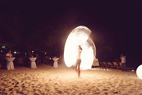 A man performing a fire act at a beach event near Infinity Bay