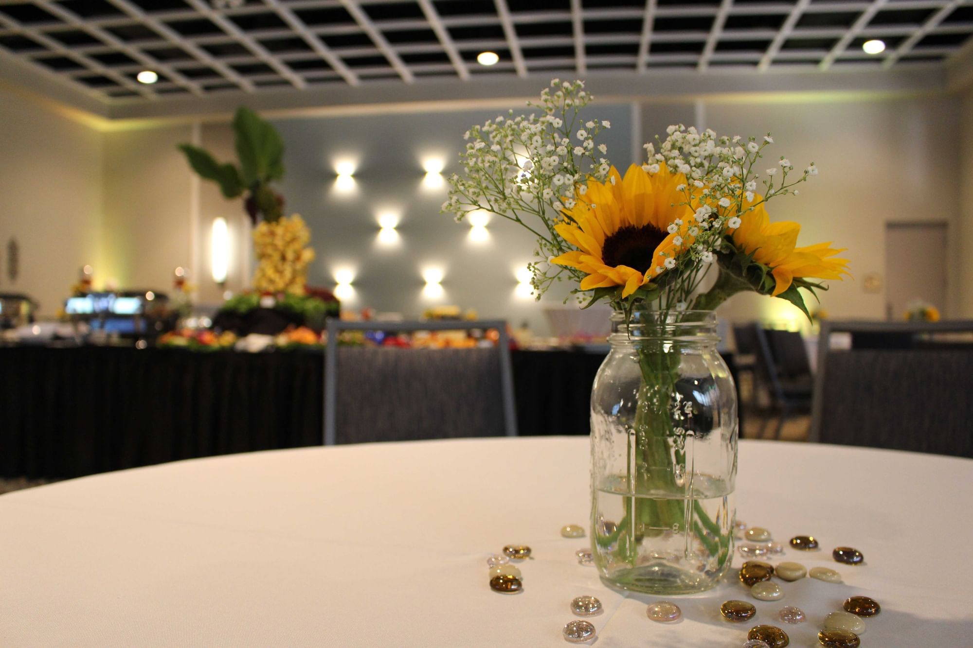 a table with flowers in a vase and a buffet in the background