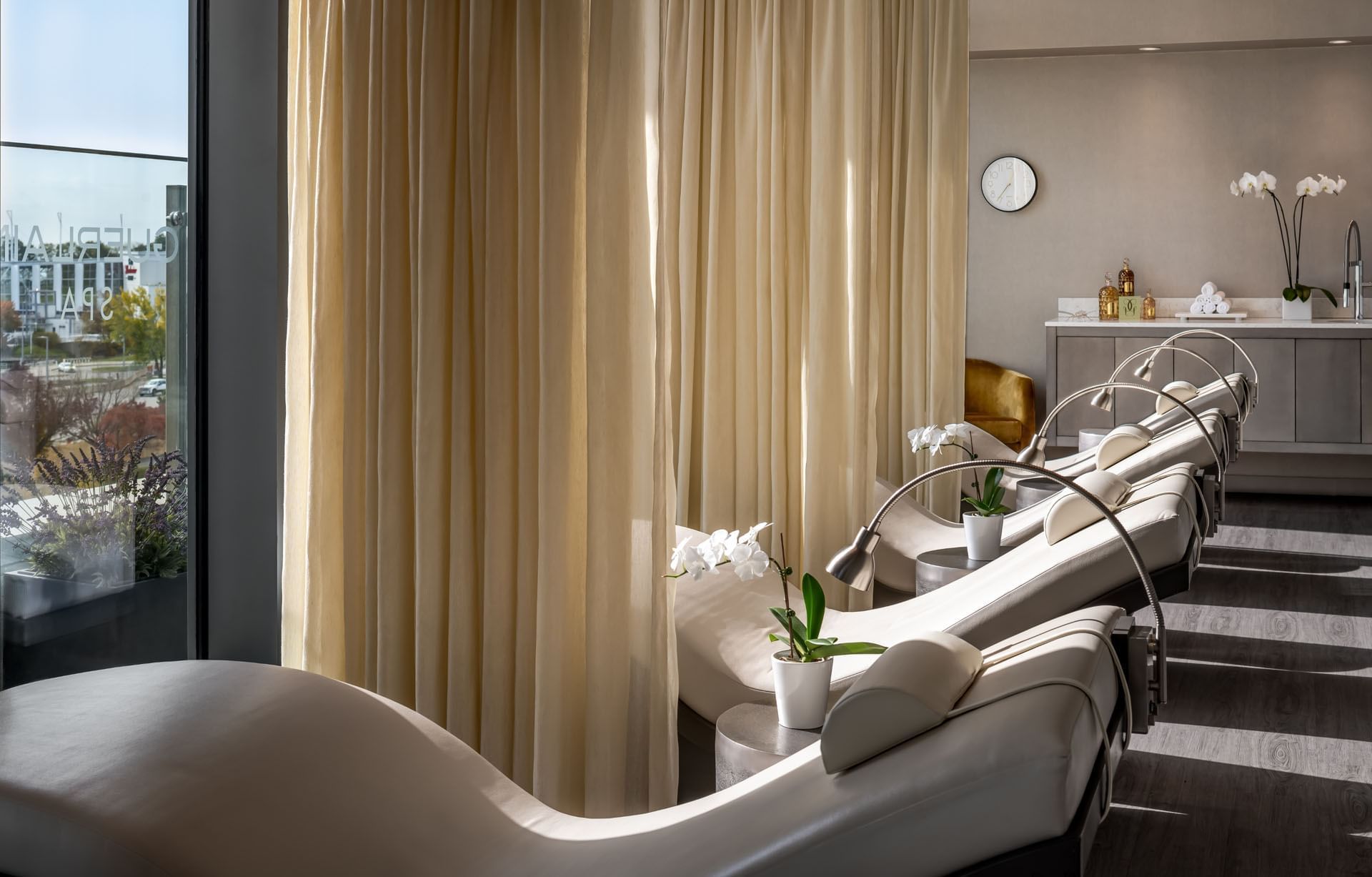 Guerlain spa interior with massage tables, elegant decor, and a city view through large windows at Hotel X Toronto